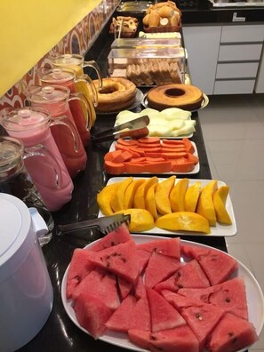 A buffet with various fruits and pastries.