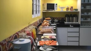 Zona de bufé con diversas opciones de comida y un microondas en la pared.