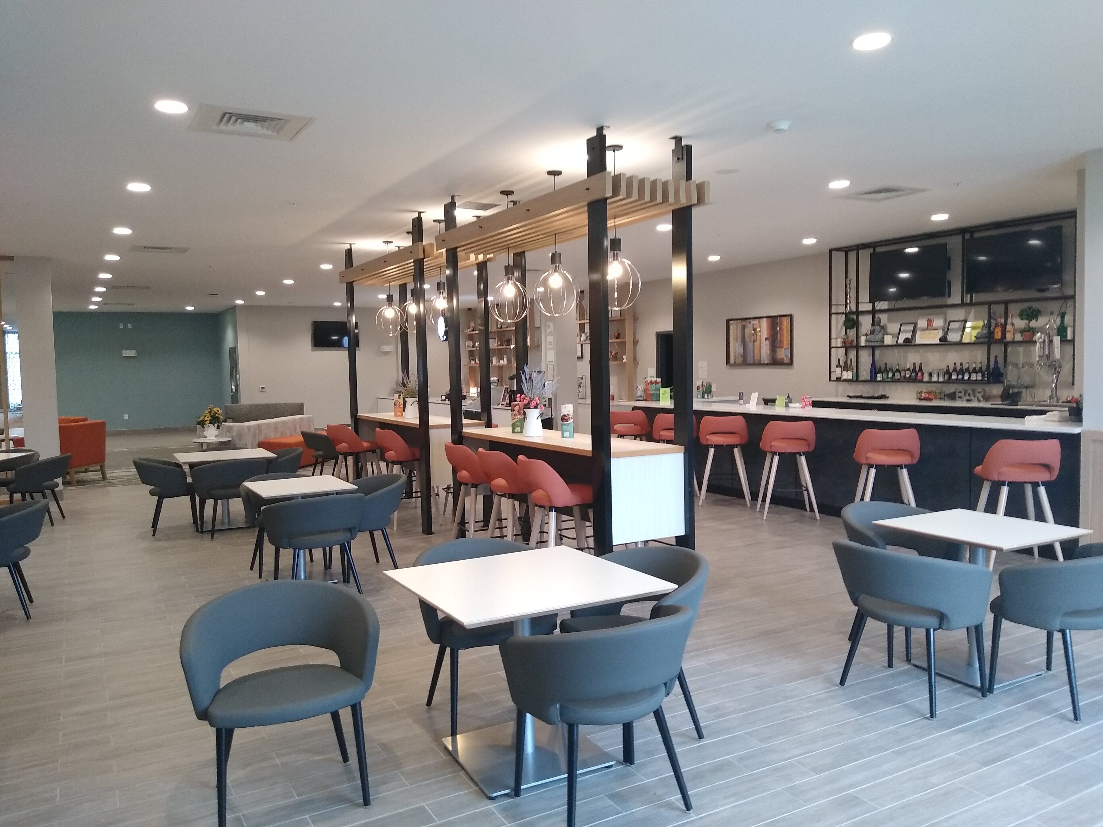 Un restaurante moderno con varias zonas de estar, incluyendo mesas, sillas y una barra.