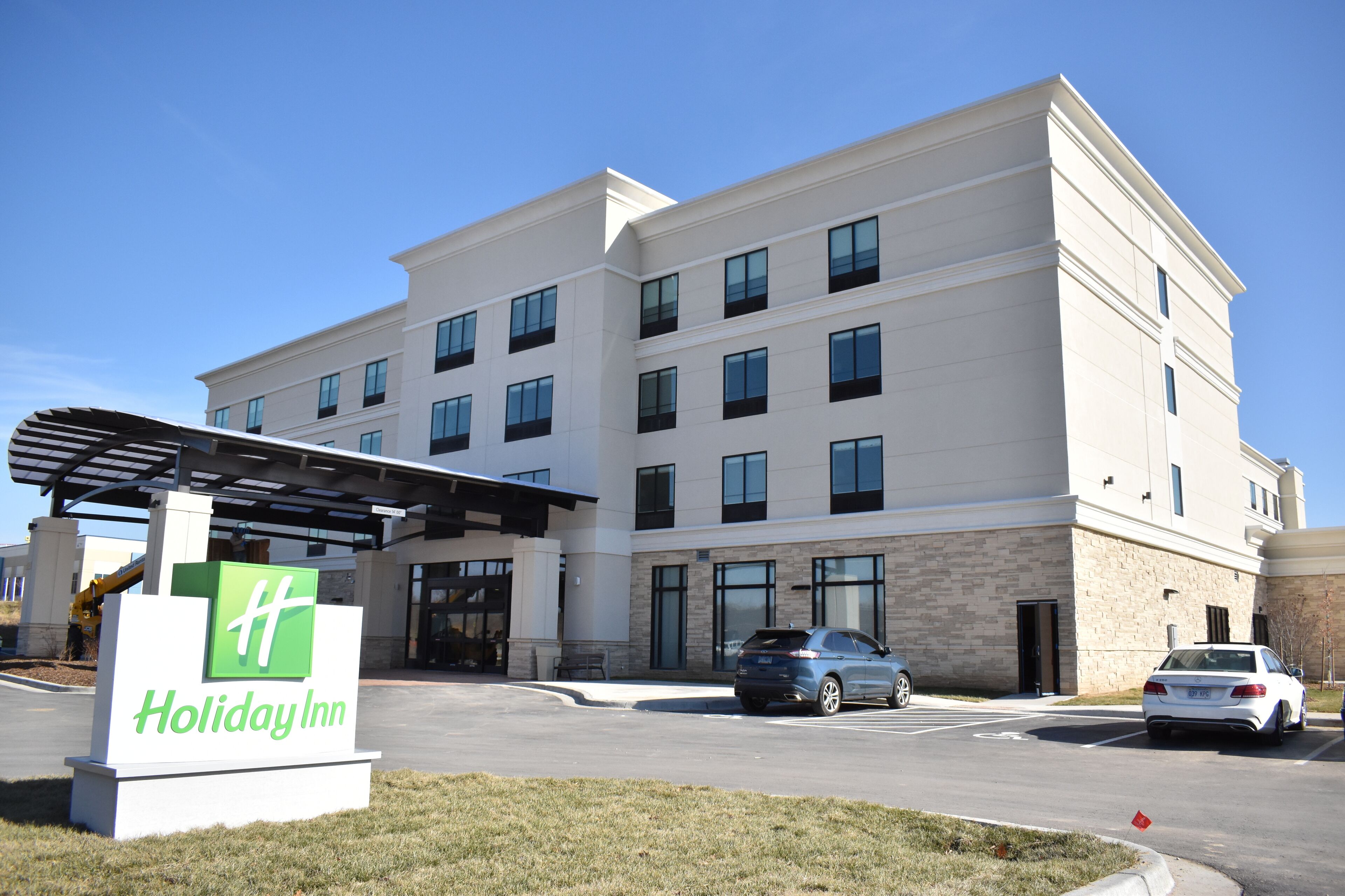 A Holiday Inn hotel with a modern design, featuring a large parking lot and a covered entrance.