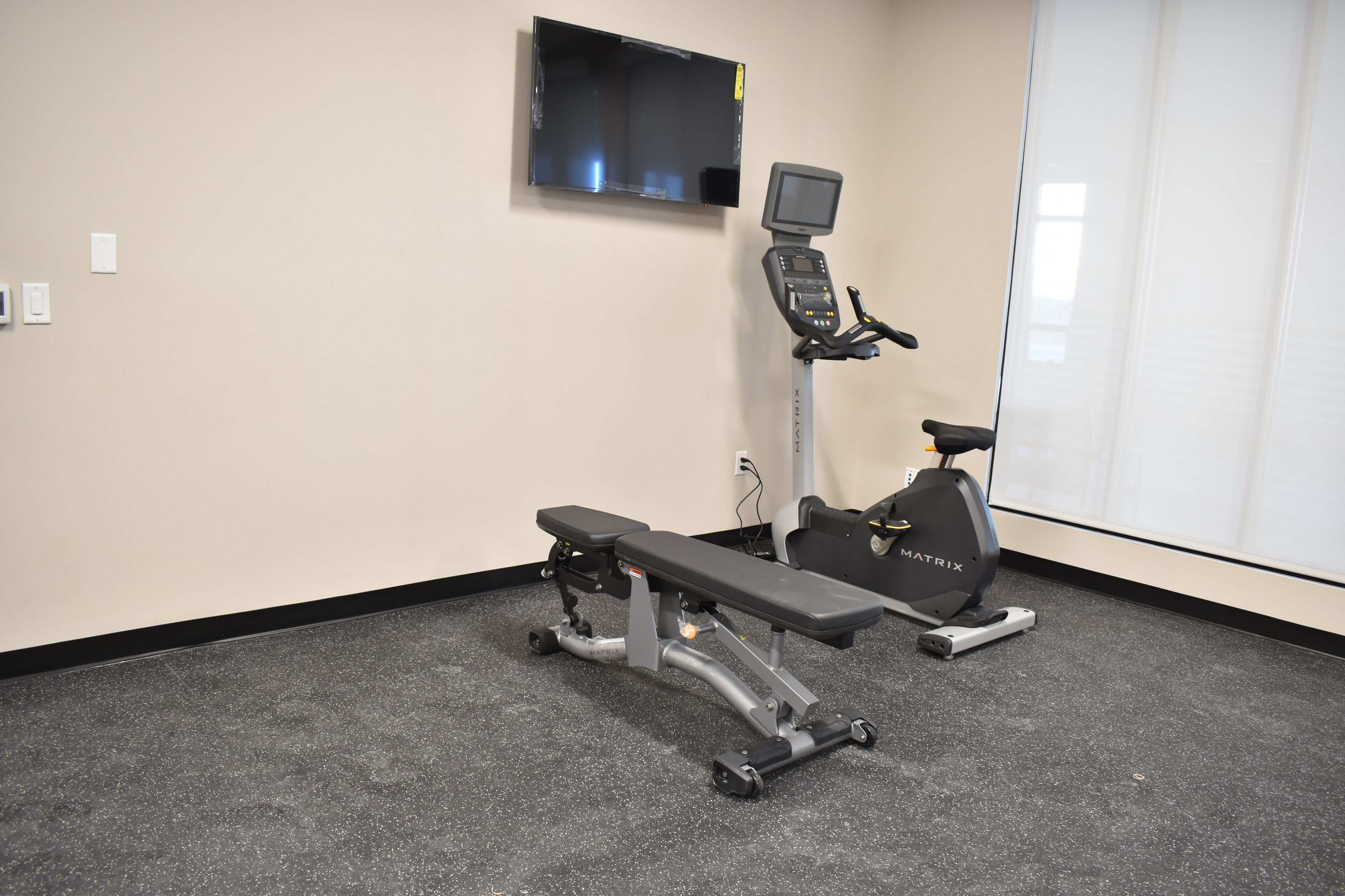 A gym with a stationary bike, a treadmill, and a bench.