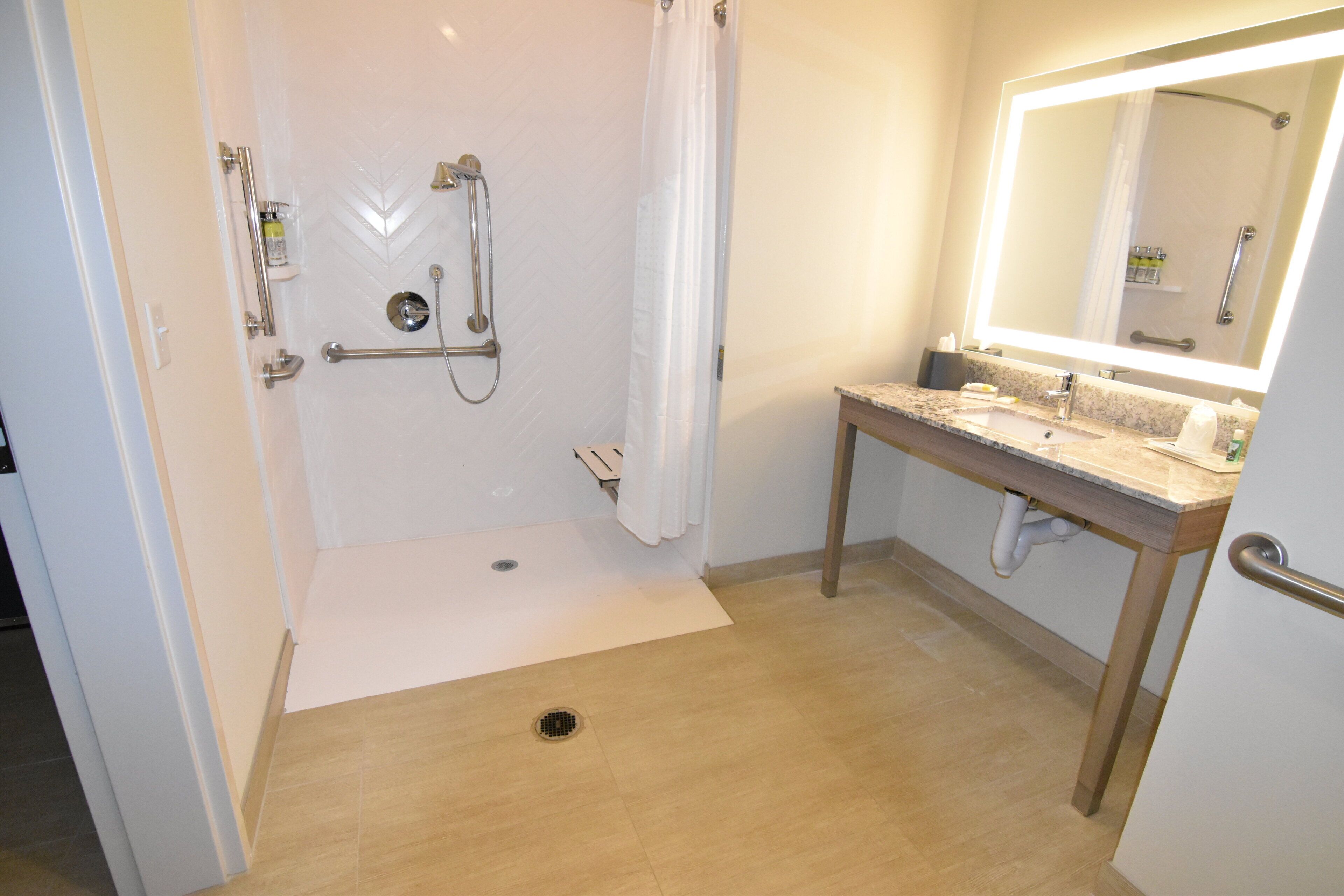 A bathroom with a shower, a sink, a mirror, and a toilet.