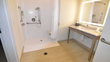 A bathroom with a shower, a sink, a mirror, and a toilet.