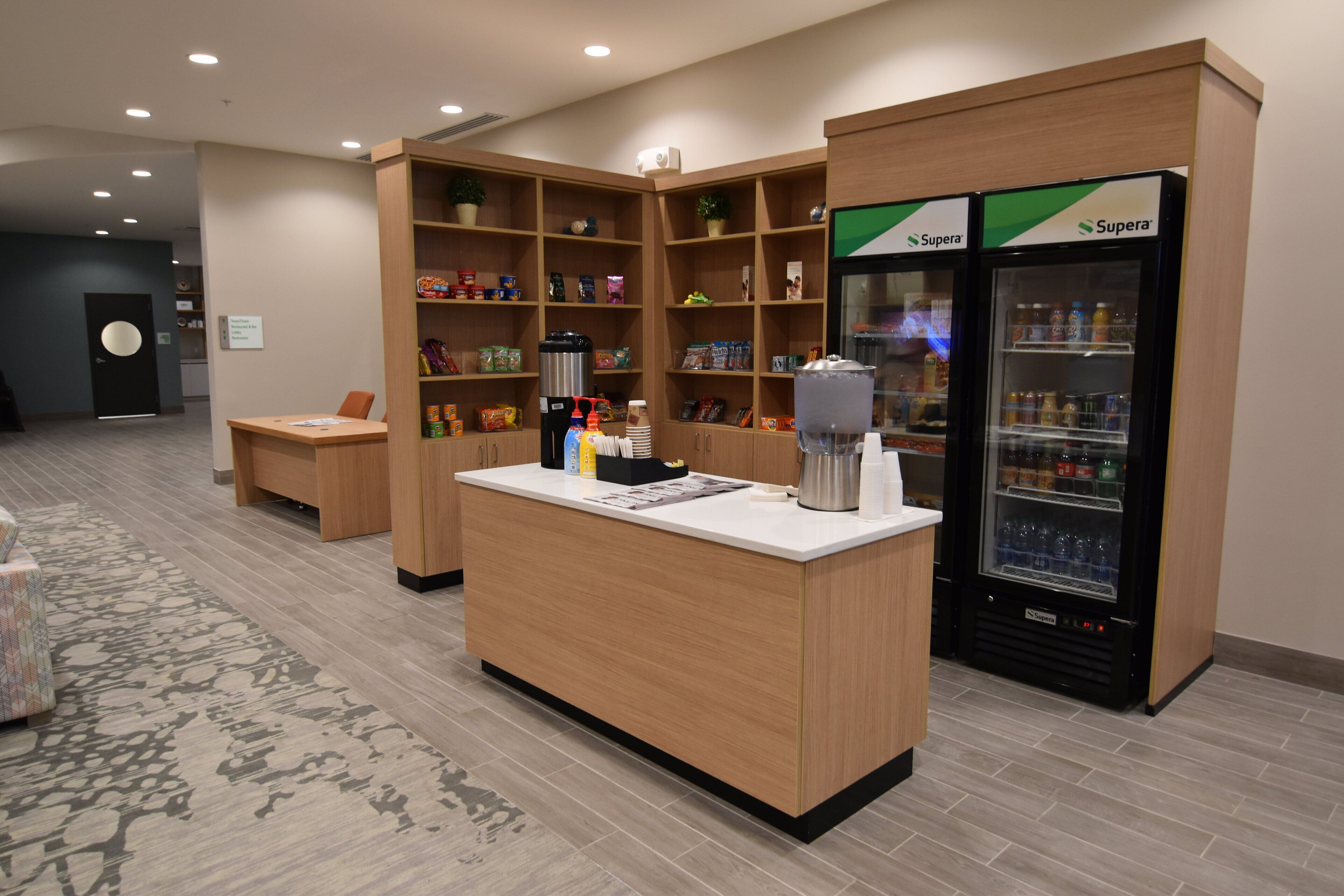 A reception area with a wooden counter, a coffee machine, and two Superera refrigerators.
