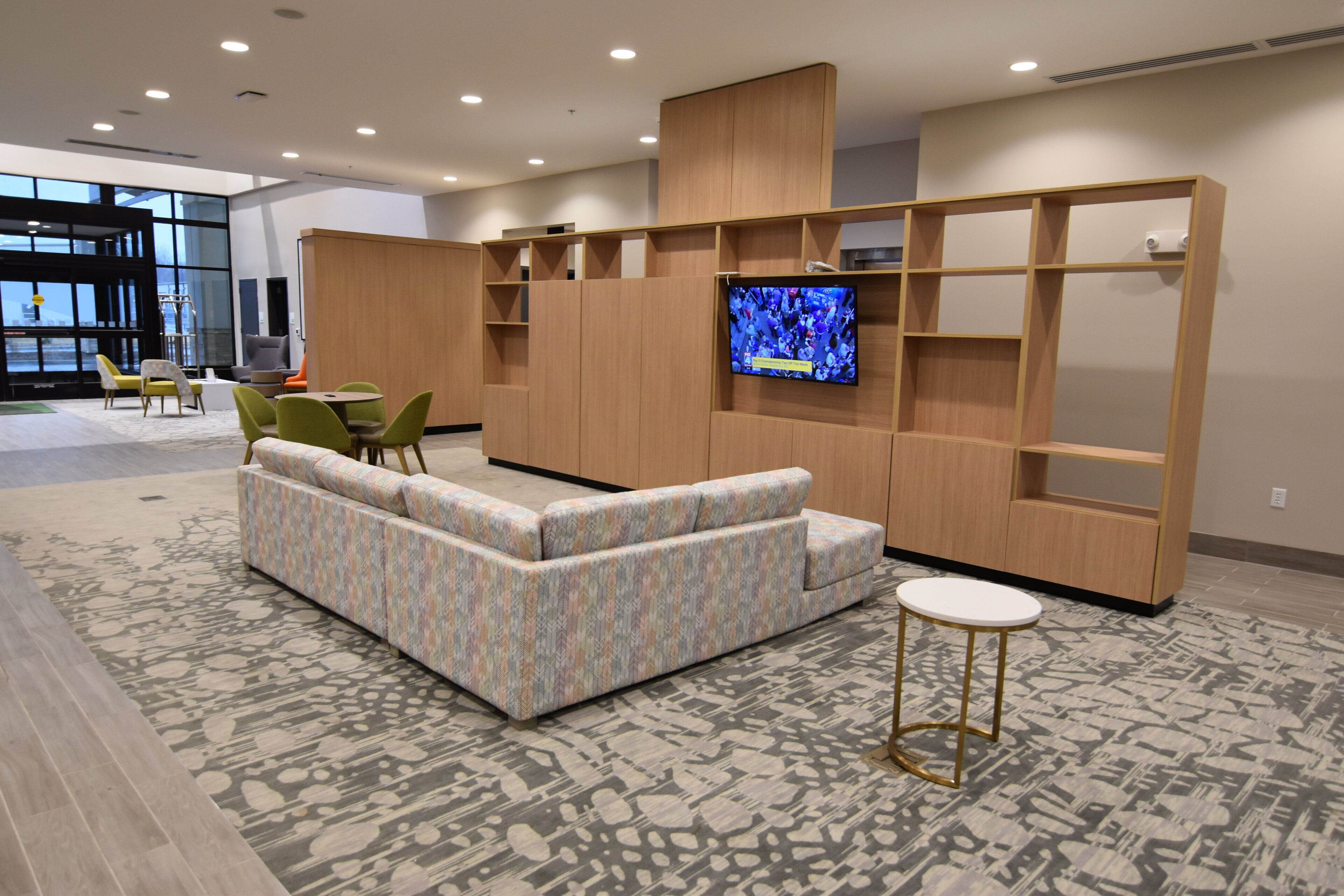 Uma área de estar moderna com sofá, cadeiras, televisão e prateleiras embutidas.