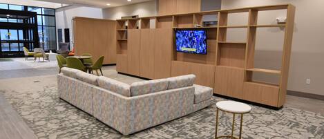 Uma área de estar moderna com sofá, cadeiras, televisão e prateleiras embutidas.