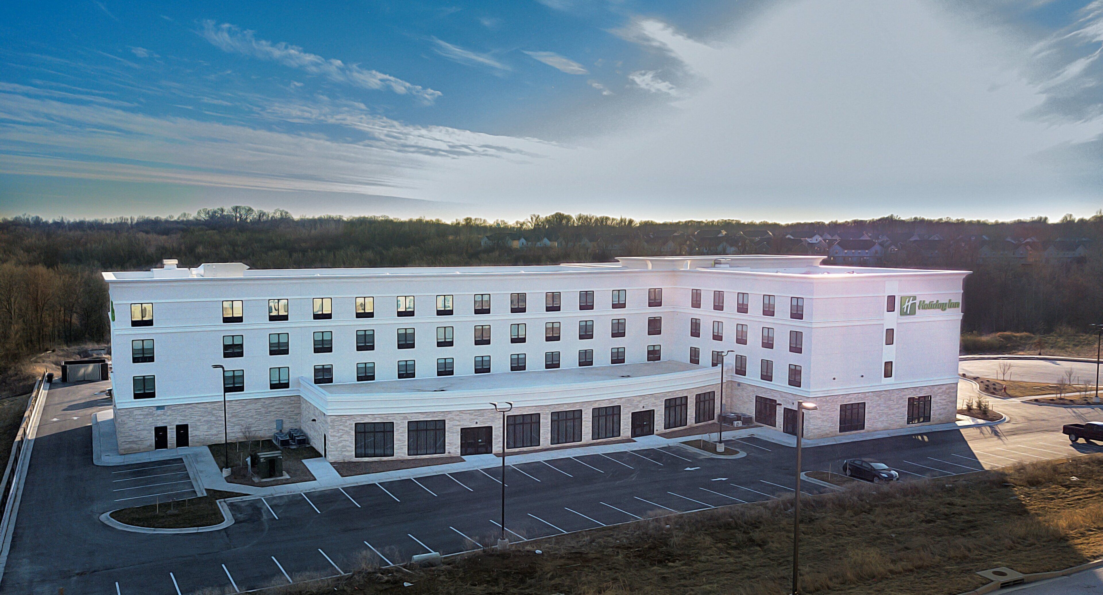 A multi-story hotel with a parking lot and a landscaped area.