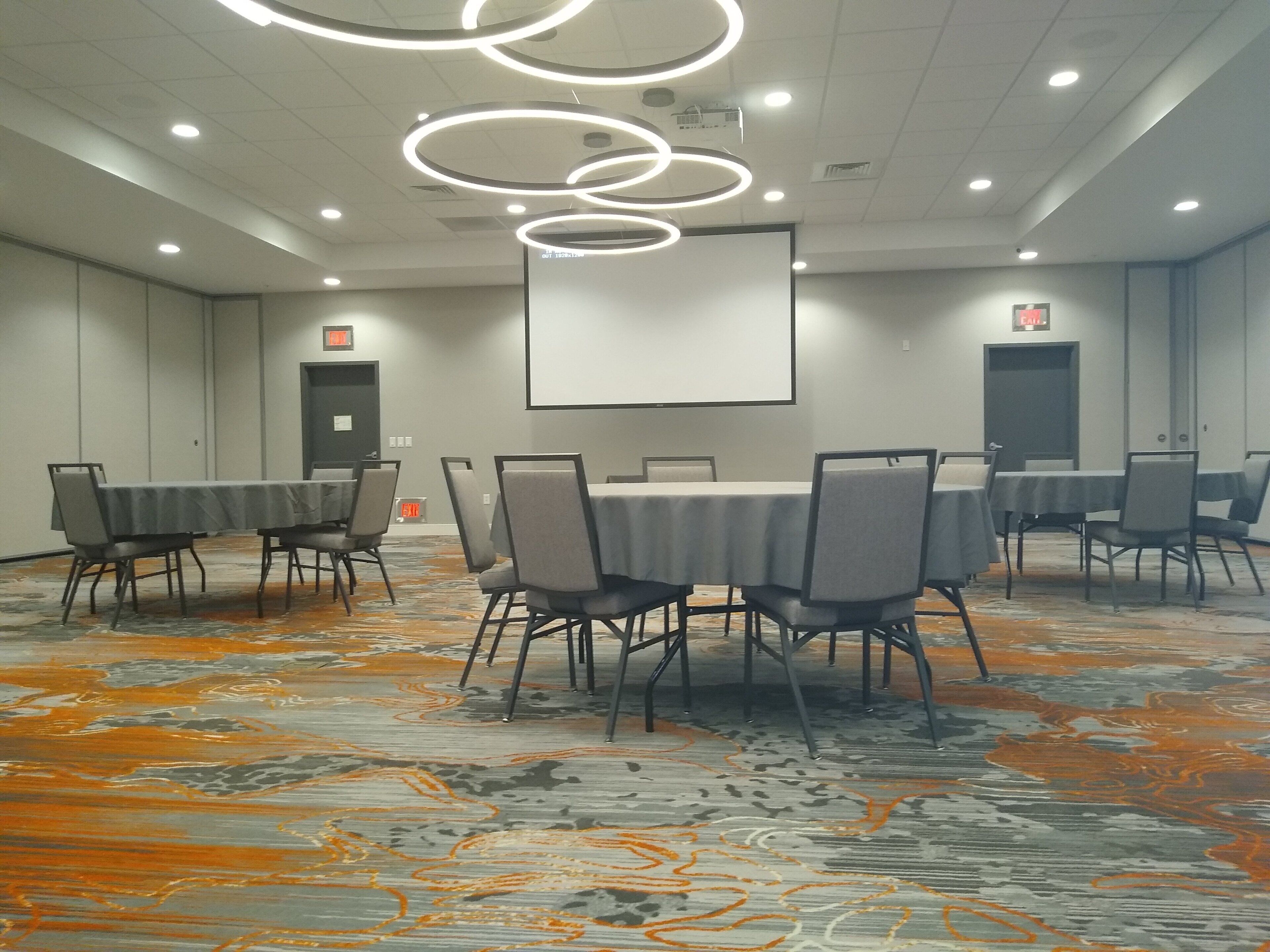 Une salle de conférence équipée d’un grand écran, de plusieurs tables et de chaises.