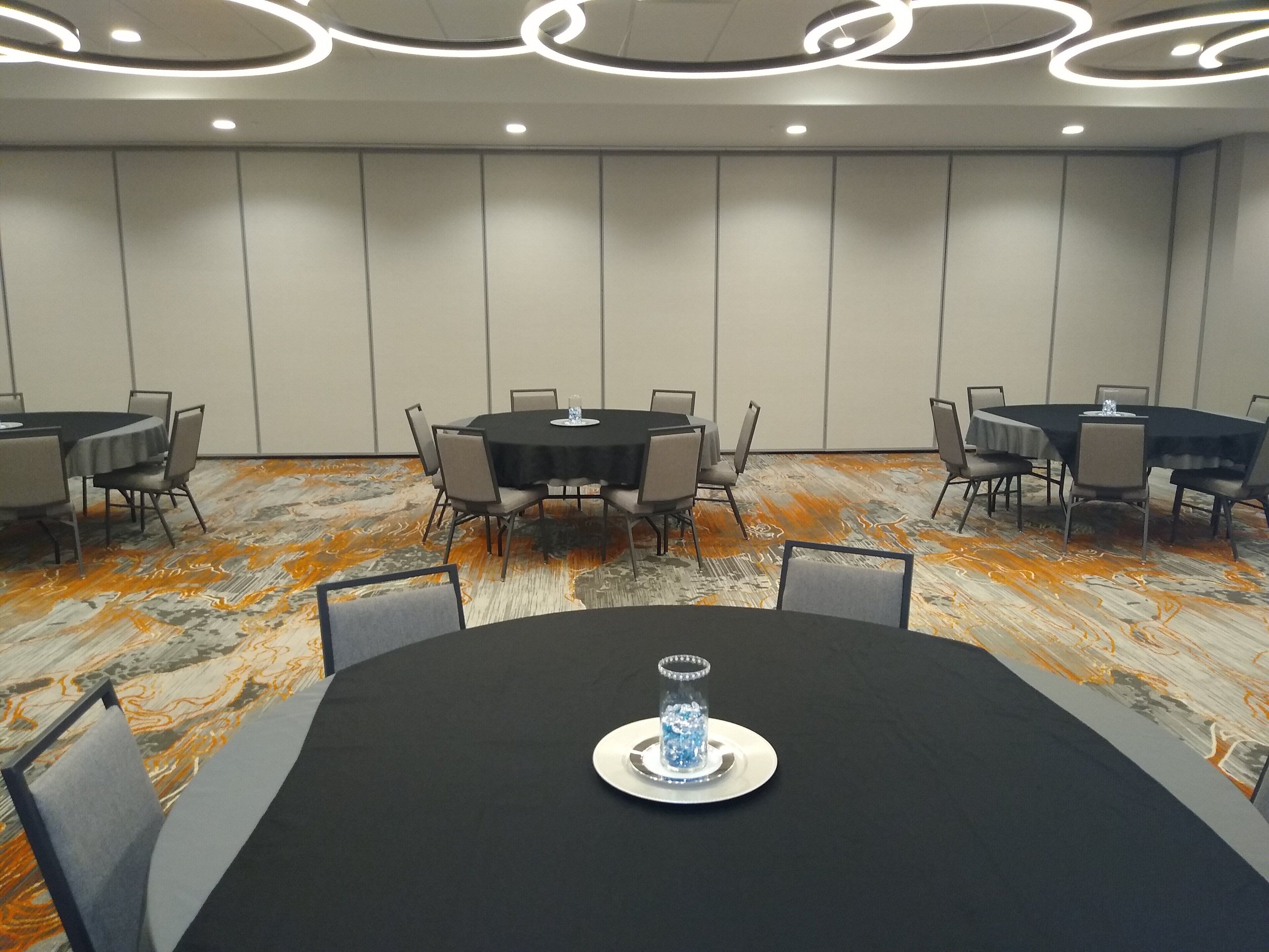 Une salle de conférence équipée de tables rondes, de chaises et d’un élément décoratif en verre au centre.