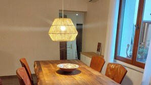A wooden dining table with chairs, a hanging light fixture, and a window with a view.
