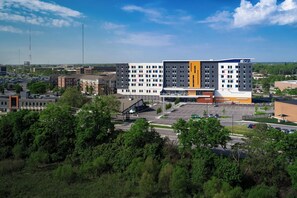 A multi-story hotel with a central atrium, parking lot, and surrounding greenery. - Aloft by Marriott Columbus University District (Columbus)