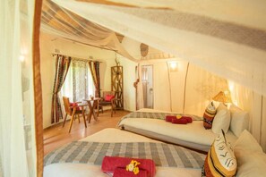 A room with two beds, a dining area, and a window with curtains.