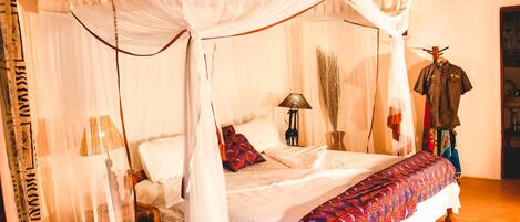A four-poster bed with a canopy, a bedside lamp, and a patterned bedspread.