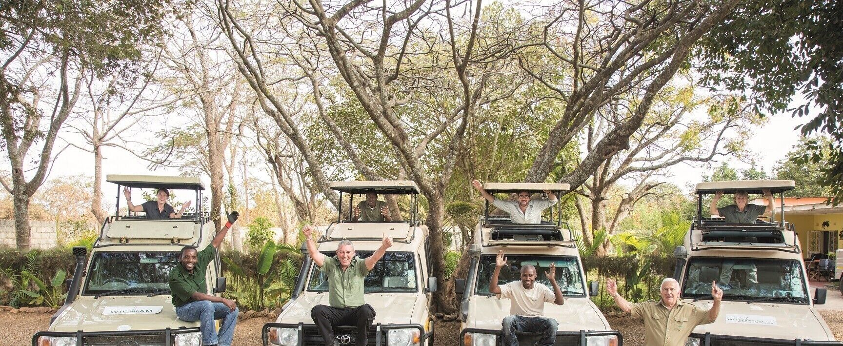 Four vehicles with raised hoods, parked outdoors with trees in the background.