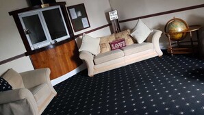 A room with a sofa, a small armchair, a globe on a stand, and a wooden cabinet. - LSO GUEST HOUSE  (Dumfries)
