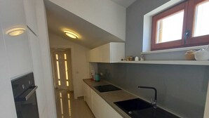 Uma cozinha moderna com uma bancada comprida, forno embutido e uma janela acima da pia.