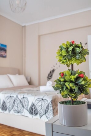 A neatly arranged bedroom with a bed, a bedside table, and a potted plant. - Fix Divine Apartment (Athens)