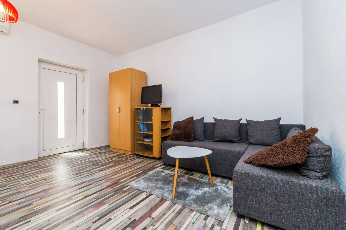 A modern living room with a grey sofa, a small white table, and a bookshelf.