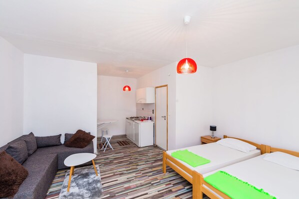 Une chambre moderne comprenant un canapé, une petite table, un lit, un bureau et un coin cuisine.