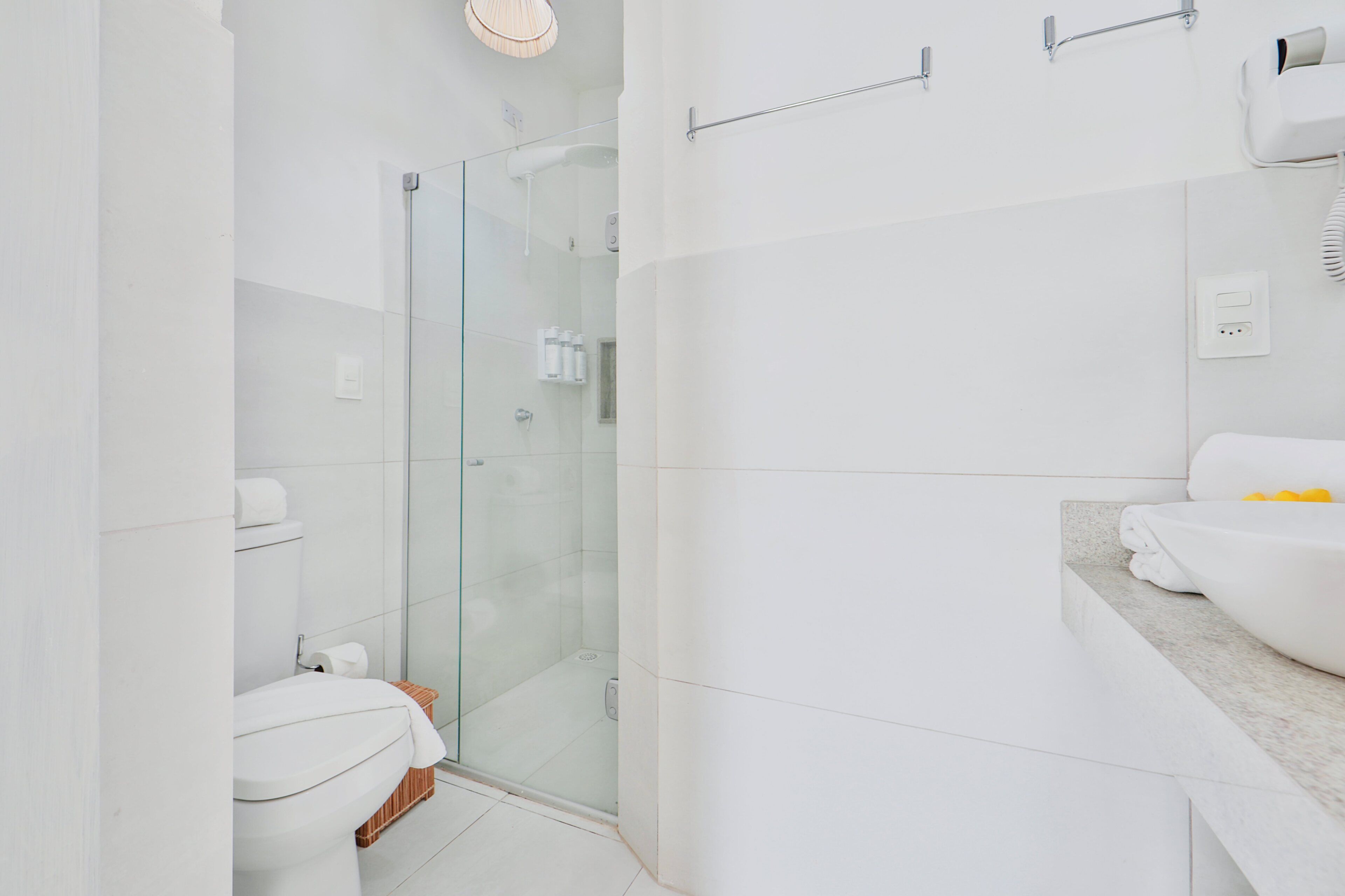 Un baño moderno con cabina de ducha de vidrio, inodoro y lavamanos con encimera de mármol.