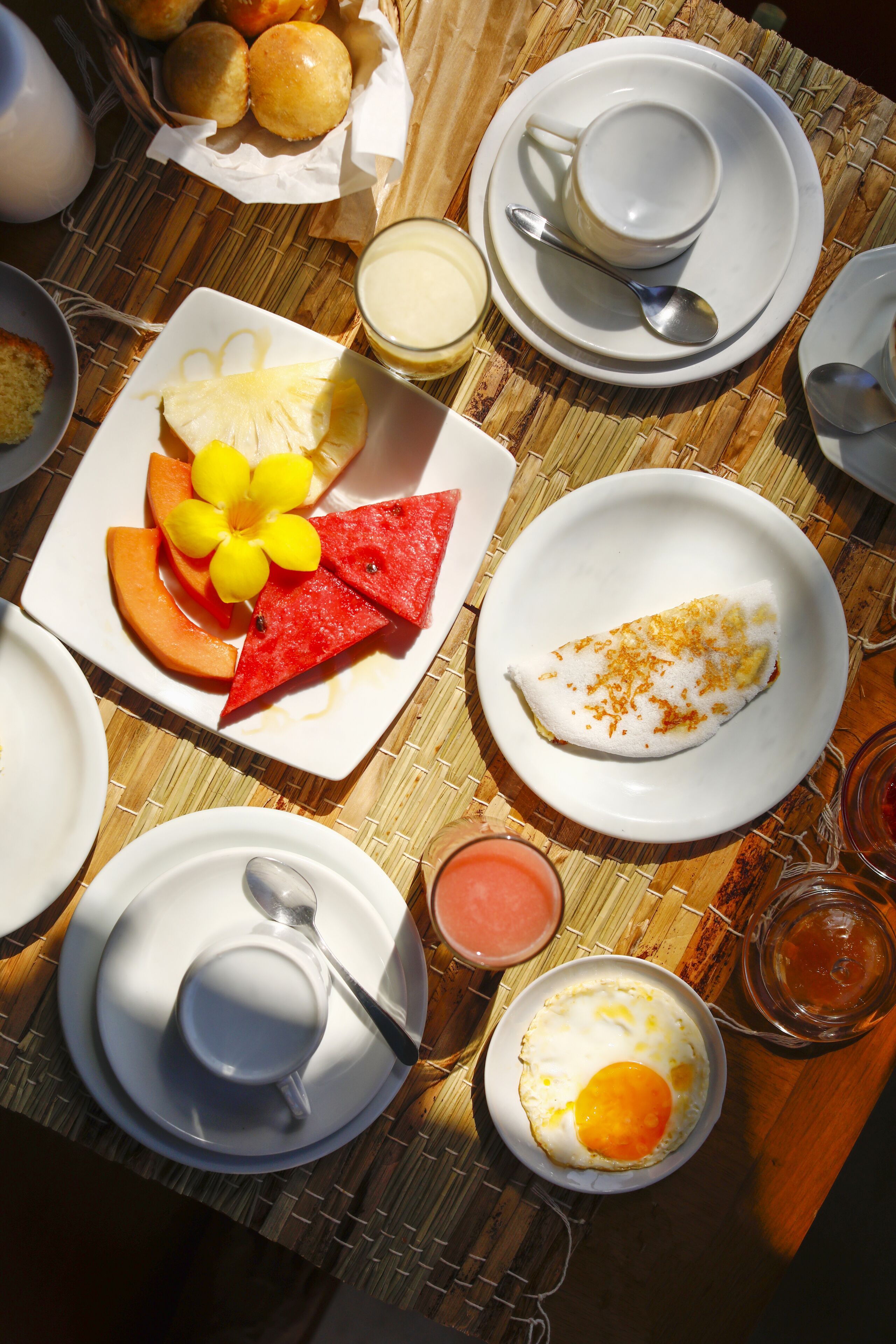 A breakfast table with plates of food, a cup, and a bowl.
