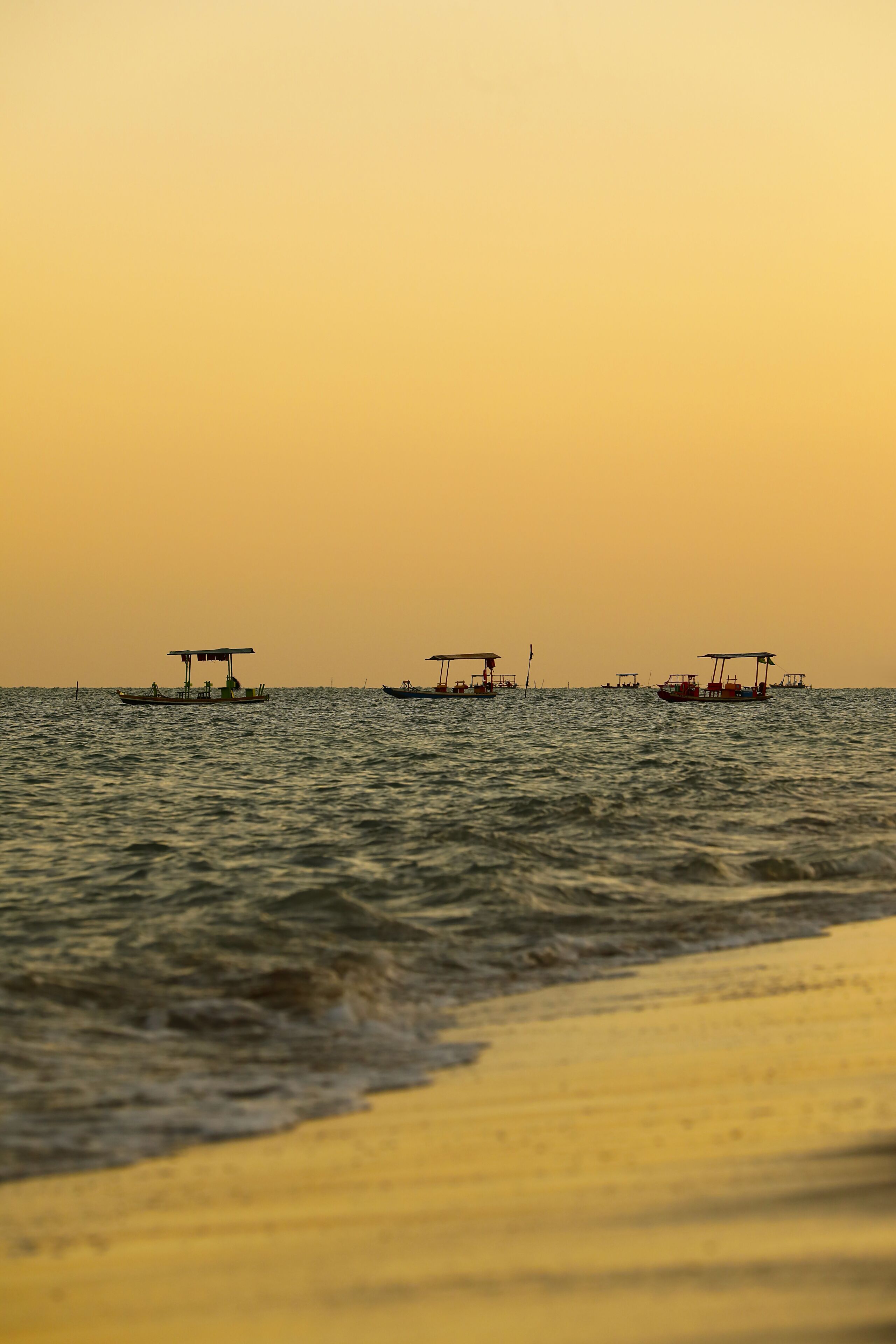 A calm sea with several boats anchored.