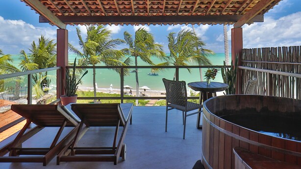 A covered outdoor seating area with a view of the beach and ocean. - Pousada Rota Ecológica (Porto de Pedras)