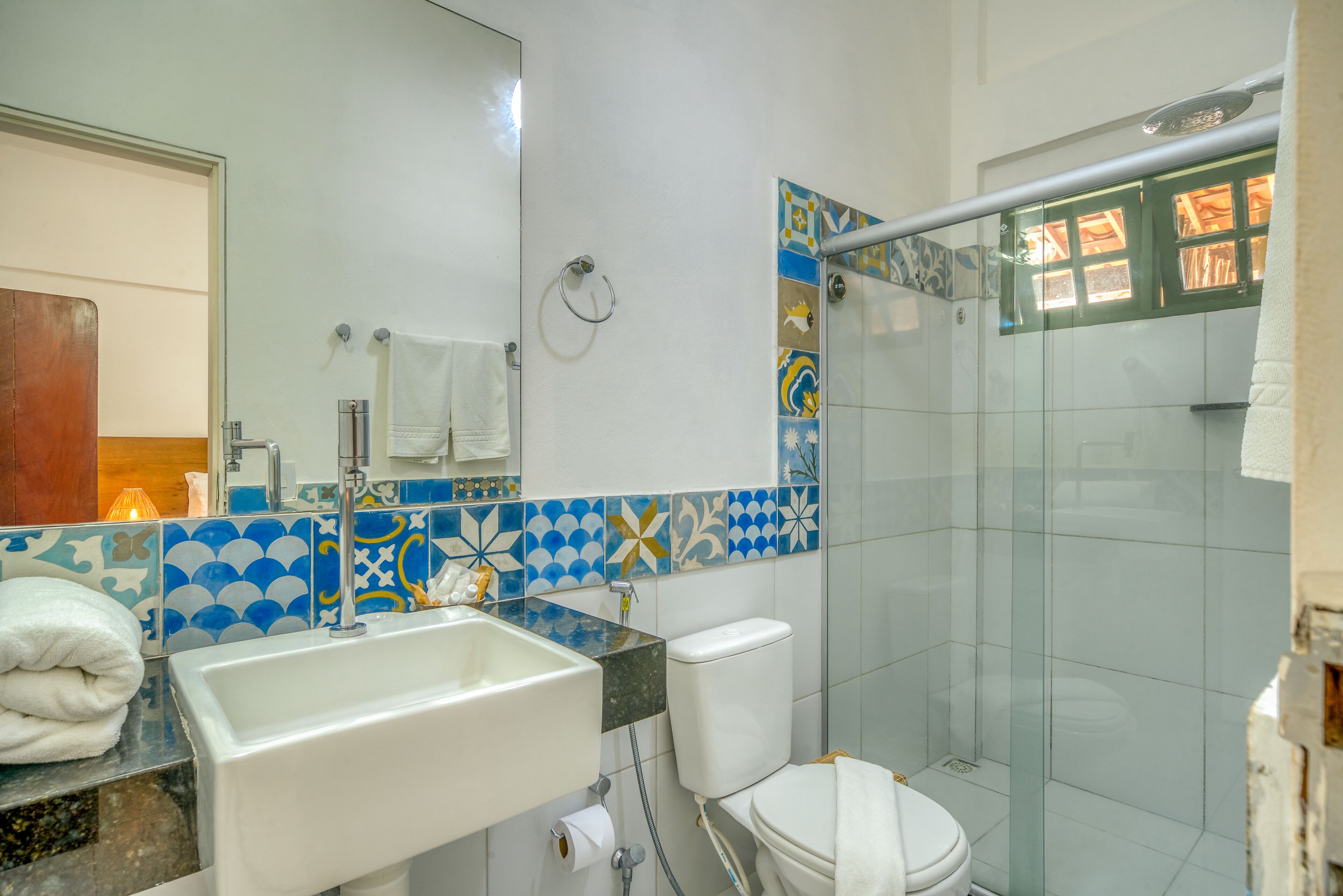 A bathroom with a sink, toilet, and glass shower enclosure.