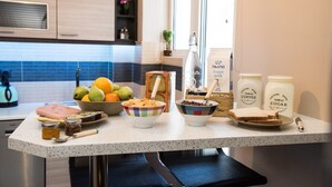 A kitchen counter with various food items, including fruits, bread, and jars of coffee and sugar. - Gazi Divine Apartment (Athens)