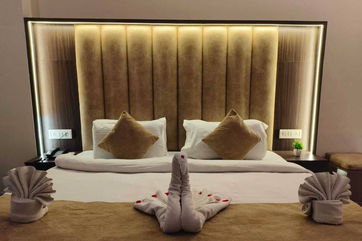 Habitación de hotel con una cama grande, dos mesitas de noche y un cabecero con iluminación integrada.