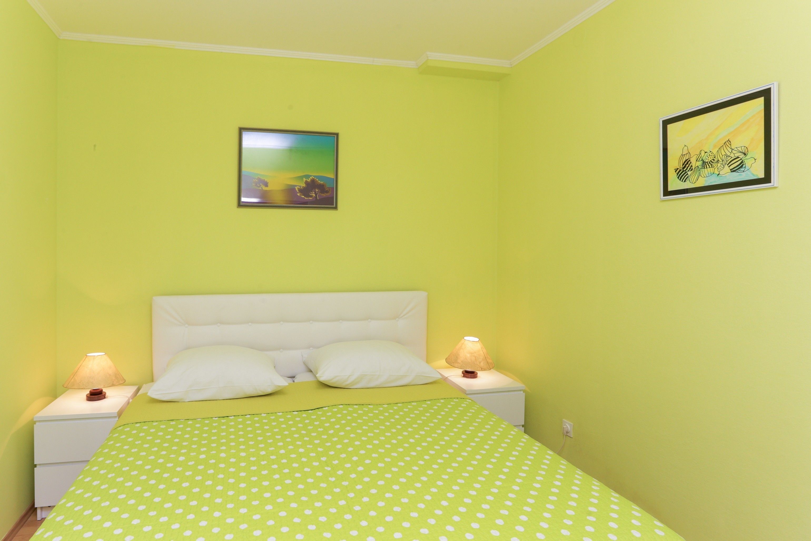 A room with a bed, two bedside tables, and two wall-mounted lamps.