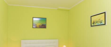 A room with a bed, two bedside tables, and two wall-mounted lamps.