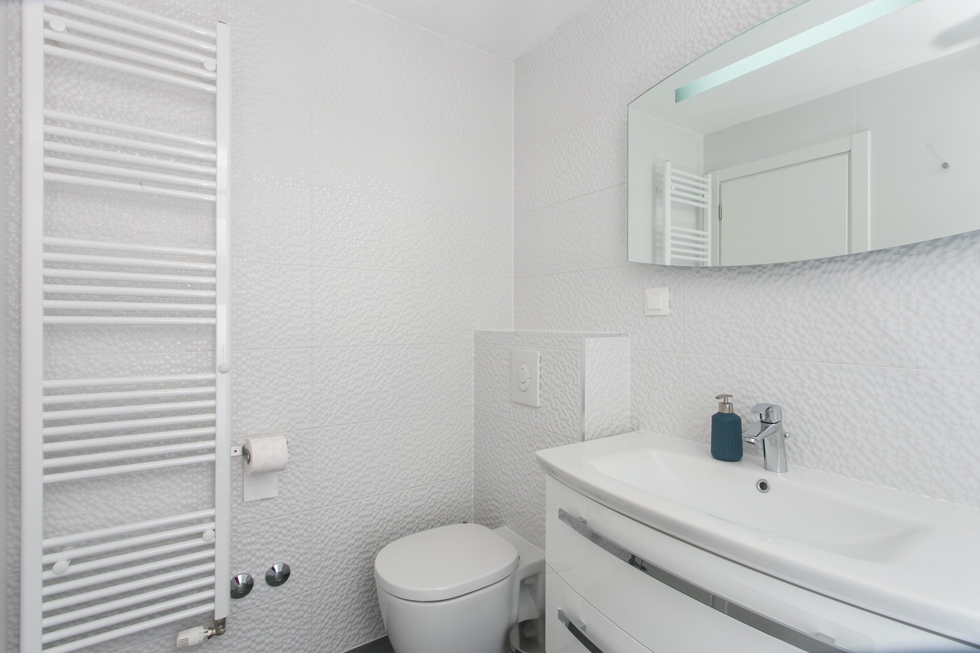 Een moderne badkamer met een wit toilet, een witte wastafel en een handdoekhouder.
