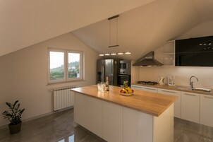 Una cocina moderna con una isla de madera, electrodomésticos de acero inoxidable y vistas al exterior.