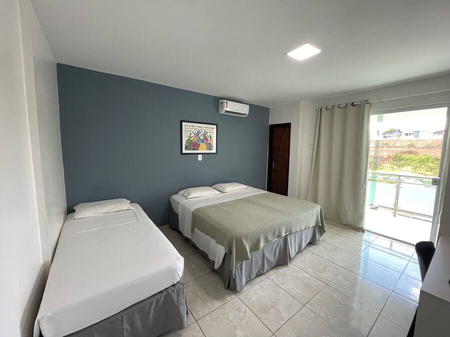 Habitación de hotel con dos camas, un ventanal con cortinas y aire acondicionado instalado en la pared.