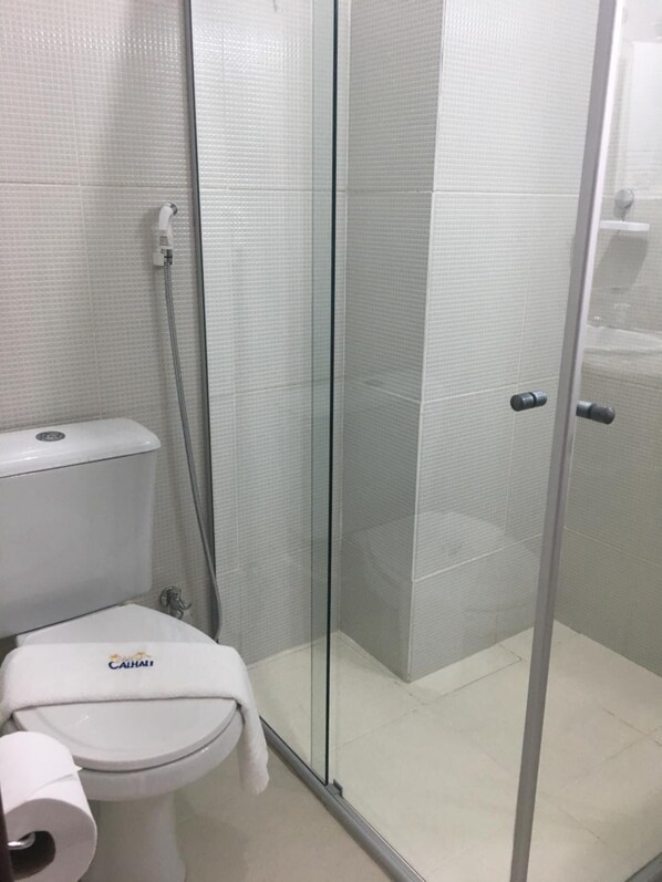 Un baño con inodoro, cabina de ducha y puerta de cristal.