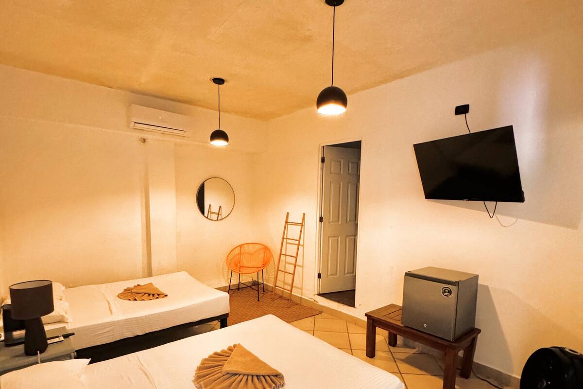 A hotel room with two beds, a TV, a desk, and a chair.