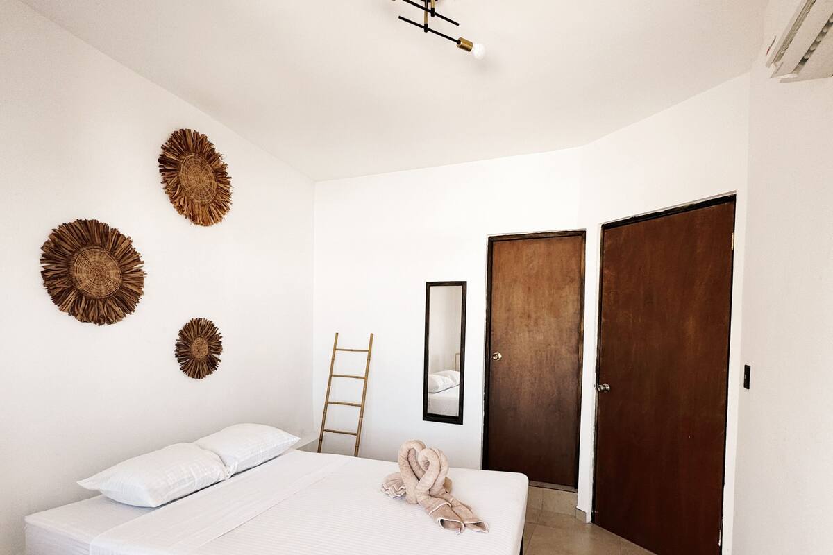 A bedroom with a bed, a wooden door, a ladder, and wall decor.