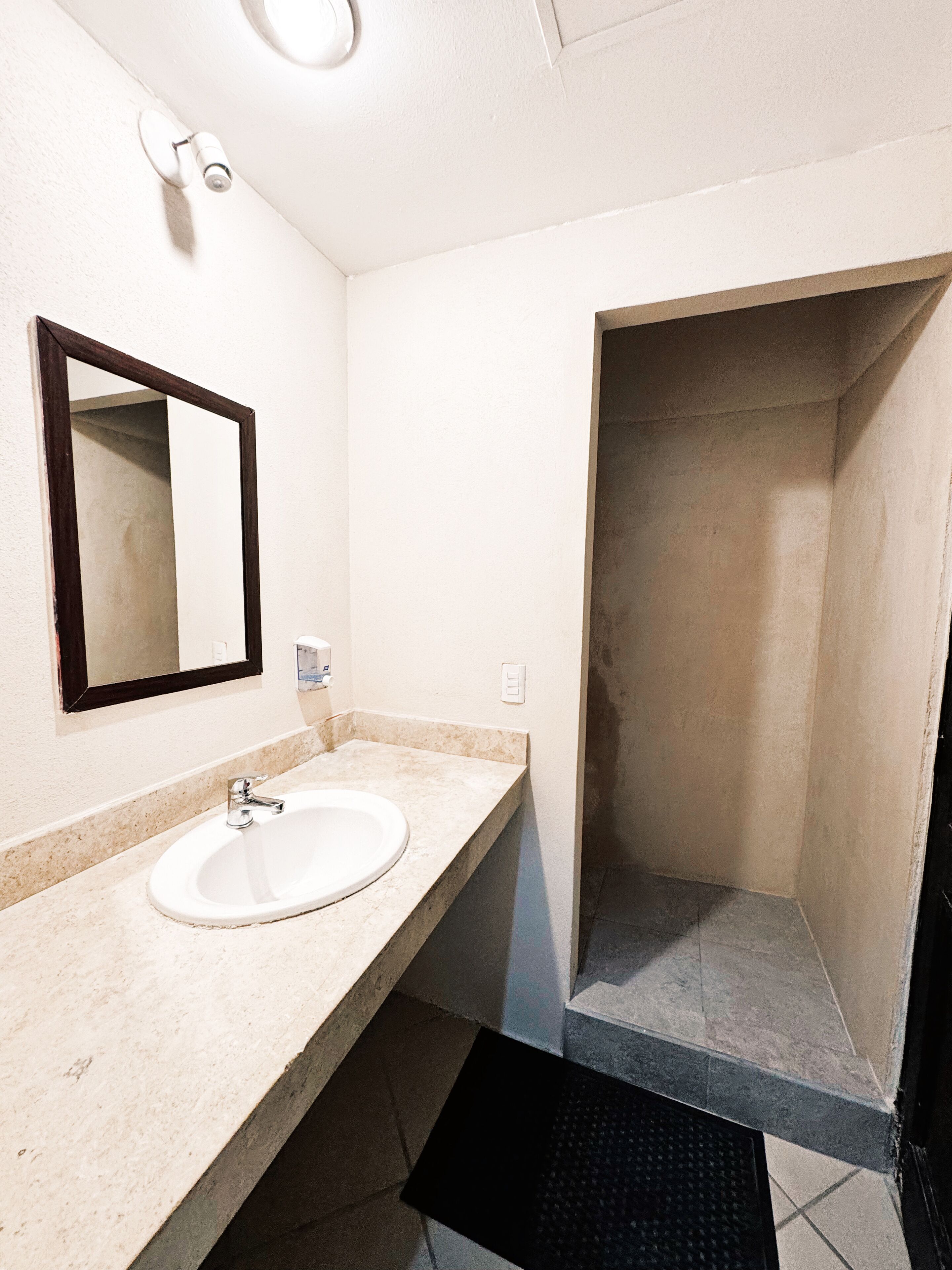 A bathroom with a white sink, a mirror, and a shower stall.