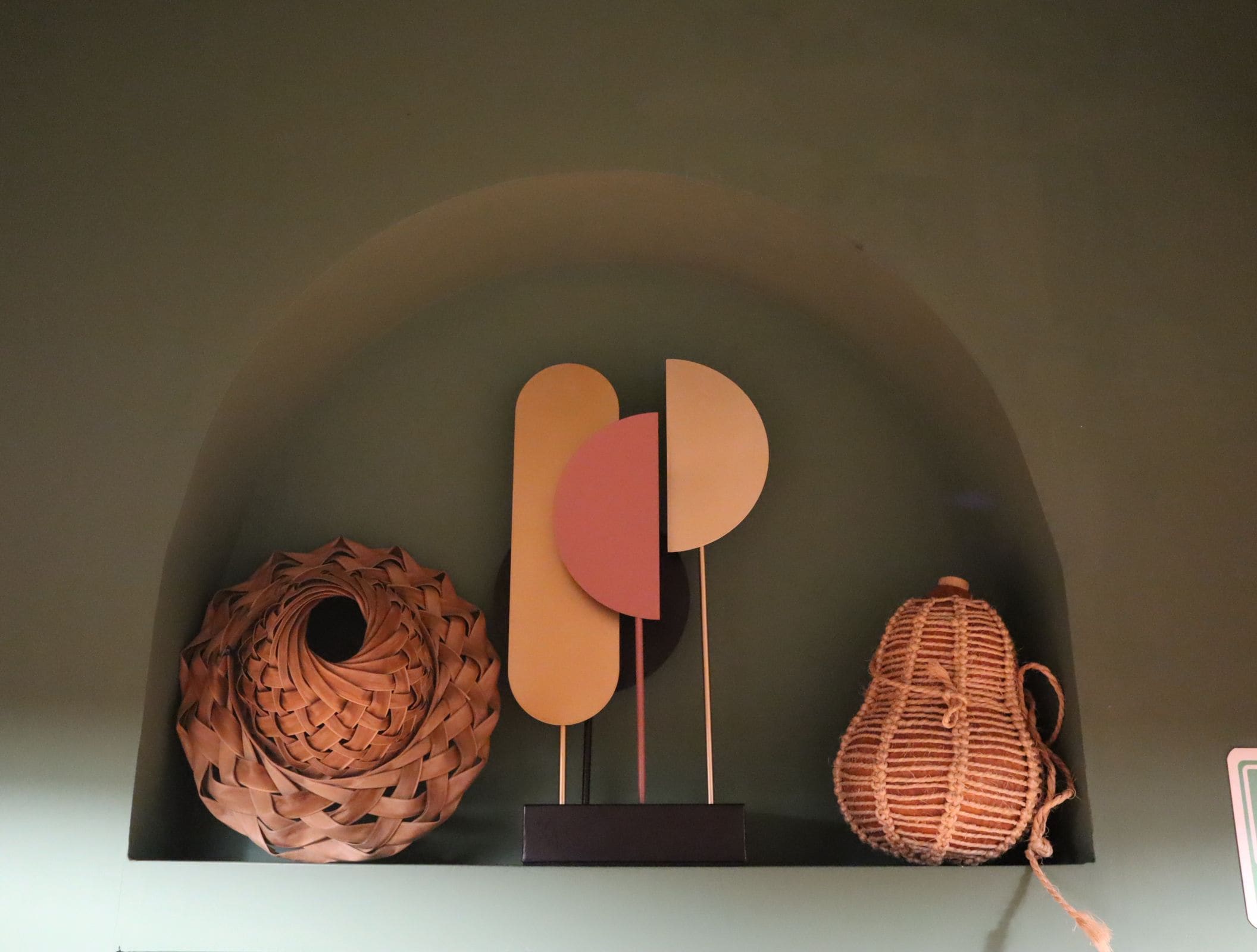 A display of three woven objects on a shelf.