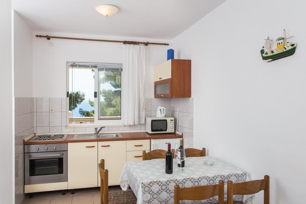 Une cuisine compacte équipée d’une cuisinière, d’un four, d’un four à micro-ondes et d’une petite table à manger avec des chaises.