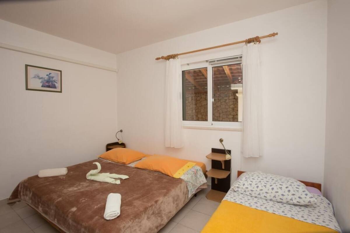 Un dormitorio con dos camas, una ventana con cortinas, un estante pequeño y un cuadro en la pared.