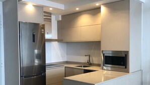 A modern kitchen with a stainless steel refrigerator, a built-in microwave, and a central island.