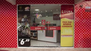 A storefront with a red and white color scheme, featuring a motorcycle advertisement and a sign for 'LOURA' with contact information. - Loura Pousada (Sobral)
