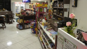 A pharmacy with shelves stocked with various products, a Coca-Cola refrigerator, and a television screen displaying a program. - Loura Pousada (Sobral)