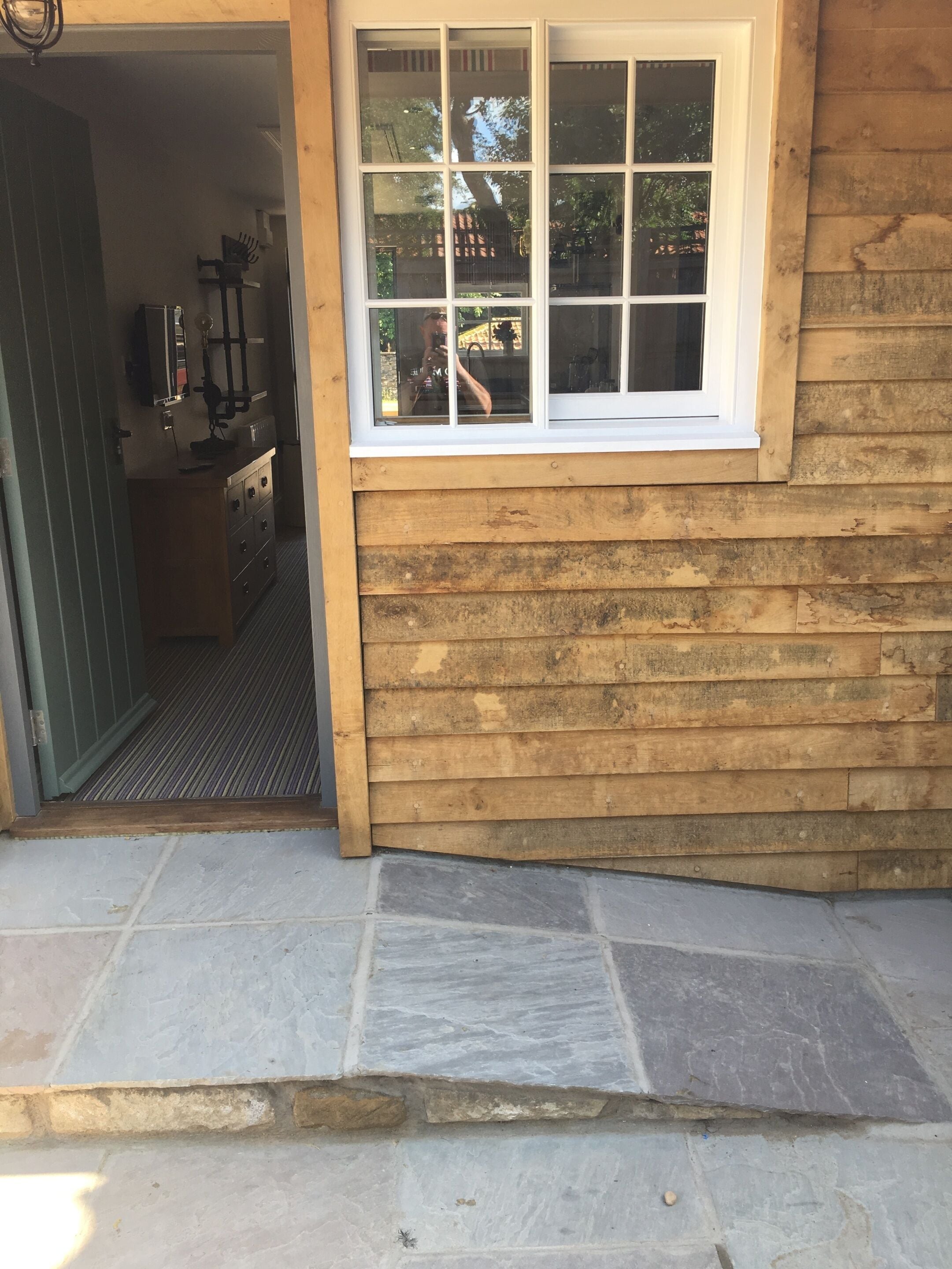 A wooden exterior with a window and a stone-paved entrance.
