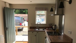 A compact kitchen with a sink, stove, and a window with a striped valance. - The Crown - Hutton le Hole (York)