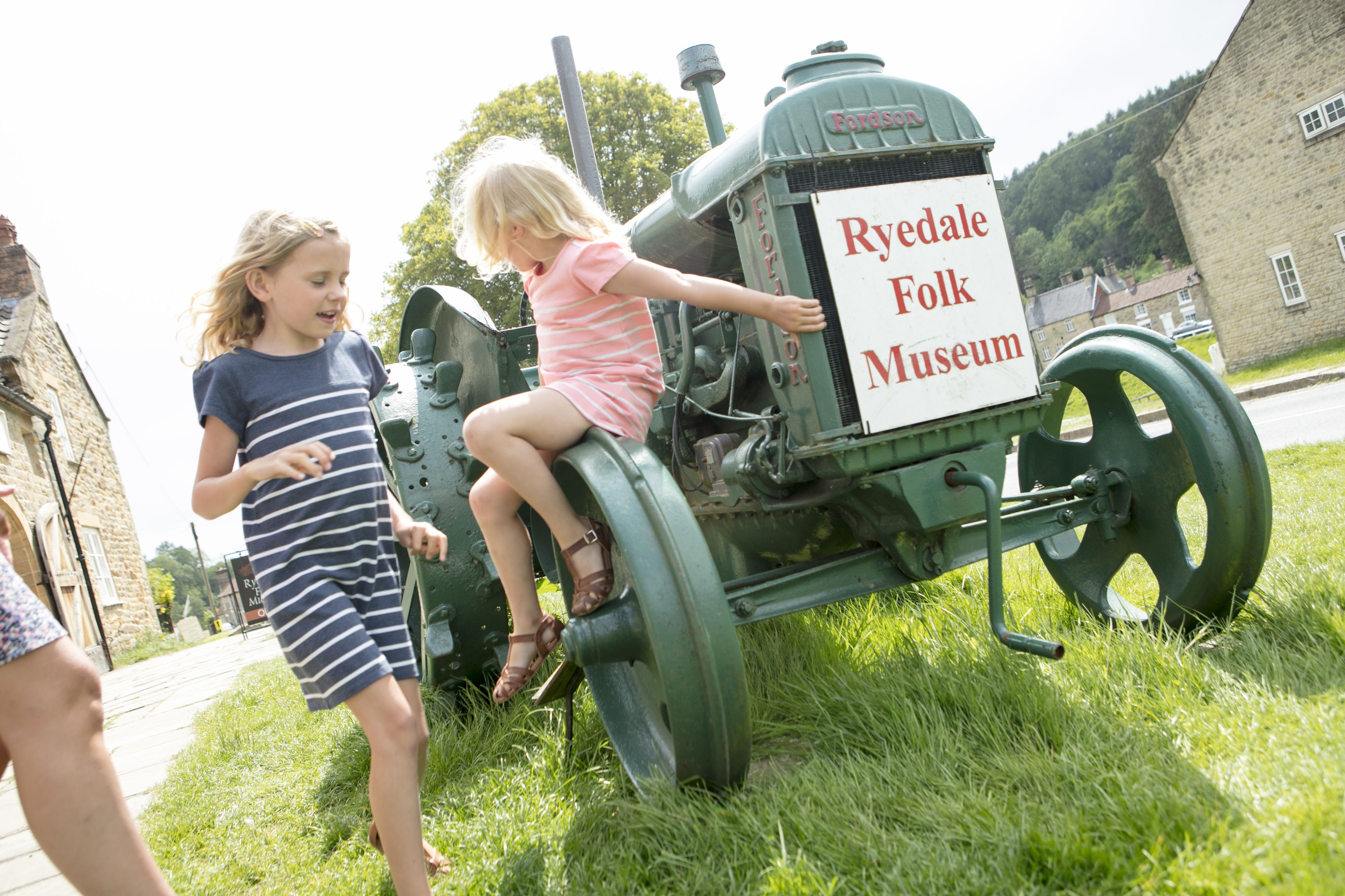 Un tractor verde con un cartel que dice 'Ryedale Folk Museum' estacionado sobre césped.