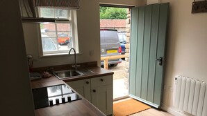 A compact kitchen with a sink, cabinets, and a window overlooking a parking area. - The Crown - Hutton le Hole (York)