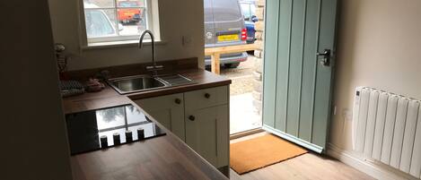 A compact kitchen with a sink, cabinets, and a window overlooking a parking area.